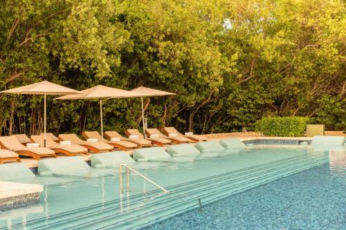 a swimming pool with lounge chairs and umbrellas at Paradisus by Meliá La Perla - Adults Only - Riviera Maya - All Inclusive in Playa del Carmen