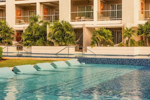 a hotel swimming pool with blue chairs in front of a building at Paradisus by Meliá La Perla - Adults Only - Riviera Maya - All Inclusive in Playa del Carmen