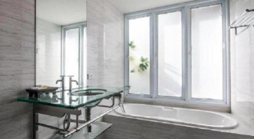 a bathroom with a tub and a sink and a window at The Living Pool Villas in Ban Ko Khwan