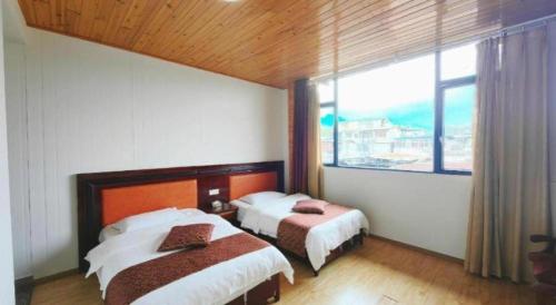 a bedroom with two beds and a large window at Mount Emei Fulin Hotel in Baoguosi