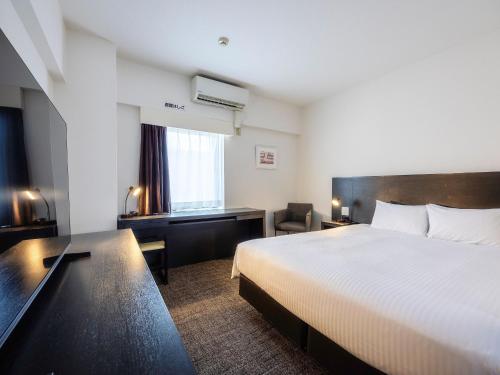 a hotel room with a bed and a desk at KOKO HOTEL Yokohama Tsurumi in Yokohama