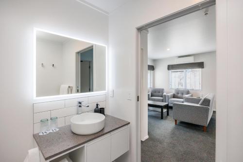 a white bathroom with a sink and a mirror at Braemar Motor Lodge in Palmerston North