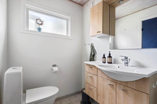 a bathroom with a sink and a toilet and a mirror at FJ4307-Oro-Gronnevej-6 in Orø