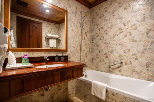 a bathroom with a sink and a tub and a mirror at Pierre Hotel in Siem Reap