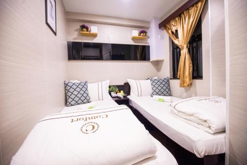 two twin beds in a room with a window at Smiley Inn in Hong Kong