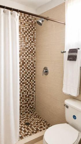 a bathroom with a shower with a toilet and a shower curtain at The Hideaway Suite, largest master, ocean glimpse in Florence Hall