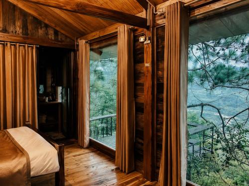 a bedroom with a bed and two large windows at Lam Ecolodge Mu Cang Chai in Nam Khat