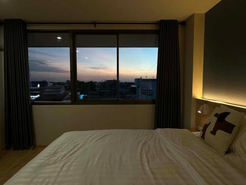 a bedroom with a bed and a large window at Tokyo Hotel in Ubon Ratchathani