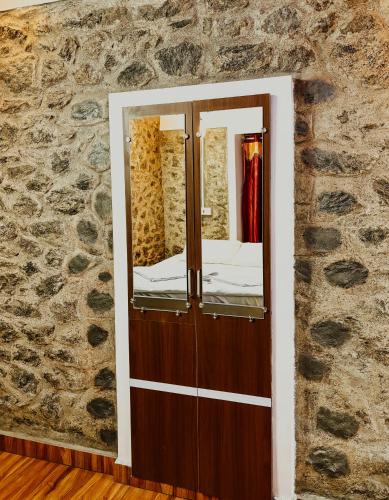 a mirror in a room with a stone wall at SpiceBuds FarmStay - Ramakkalmedu in Idukki