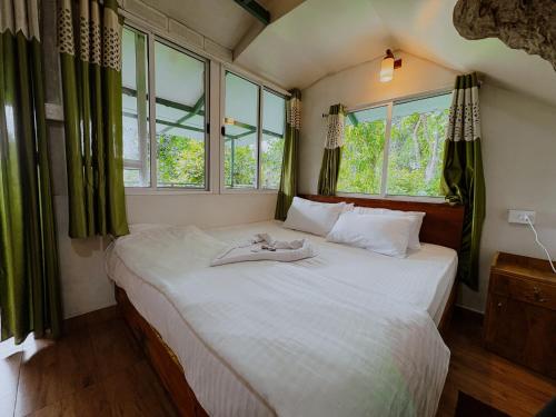 a bedroom with a white bed with windows at SpiceBuds FarmStay - Ramakkalmedu in Idukki