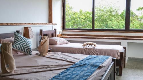 two beds in a room with two windows at Kudakalliya Beach Houses in Arugam Bay