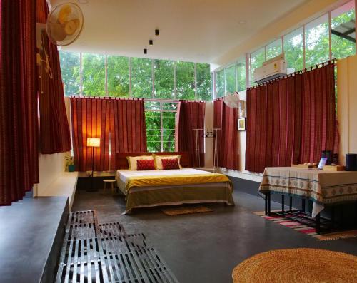 a bedroom with two beds and red curtains at Dheer- BnB at an Artist's Abode in Shānti Niketan