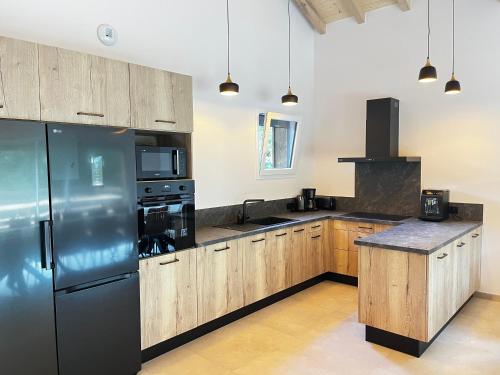 a kitchen with wooden cabinets and a stainless steel refrigerator at Chalet des Épicéas - babyfoot billard & PS in Gérardmer