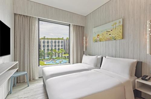 a hotel room with two beds and a window at Village Hotel Sentosa by Far East Hospitality in Singapore