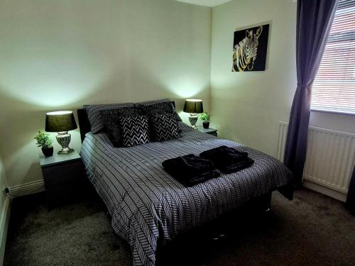 a bedroom with a large bed with two lamps on it at Miners Lamp Apartment in Easington