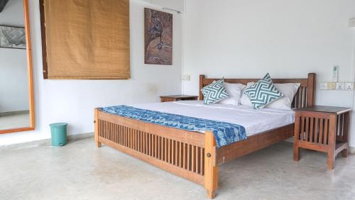a bedroom with a large wooden bed with two tables at Kudakalliya Beach Houses in Arugam Bay