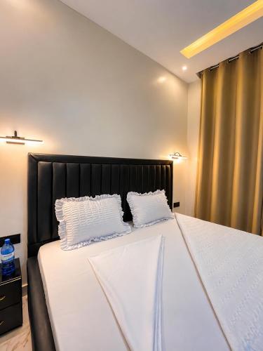 a bedroom with a large bed with two pillows at KIGALi WHITE HOMES AND RESIDENCE in Kigali