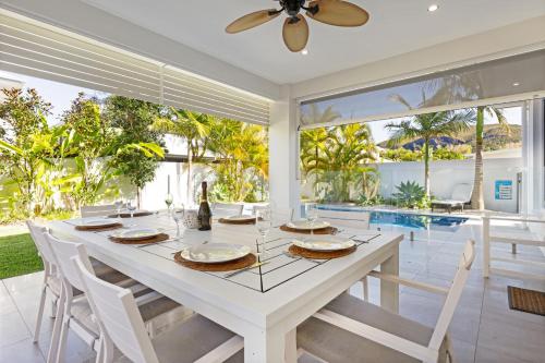 a white dining room with a white table and chairs at The Art House at Beachside in Yaroomba