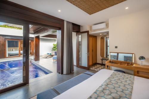 a bedroom with a pool and a bed and a desk at THE SAND Suites & Villas in Ngurah Rai International Airport