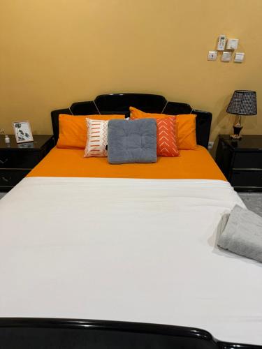 a large white bed with orange sheets and pillows at Royal Zam Résidence in Ouagadougou