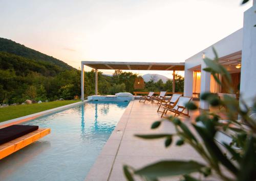 a swimming pool with lounge chairs next to a house at Aristotelia Gi - Premium Luxury Villas with Private Pools in Olympiada
