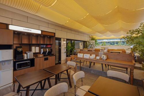 a restaurant with tables and chairs and a kitchen at NewCZ Gwangan Hotel in Busan