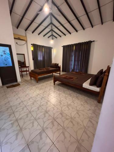 a bedroom with a bed and a couch and a tv at Serendib Villa Mirissa in Mirissa