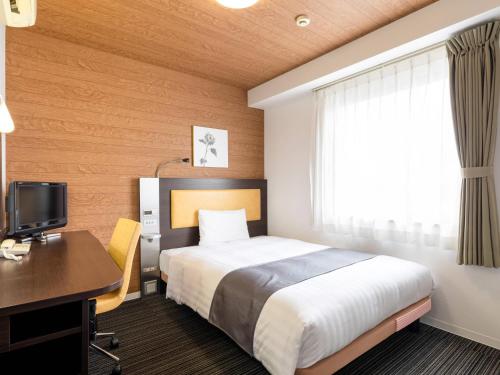 a hotel room with a bed and a desk and a computer at Comfort Hotel Kokura in Kitakyushu