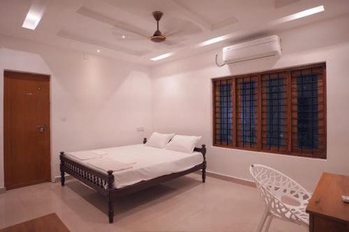 a bedroom with a bed and a window and a chair at Casa de Victoria in Alleppey