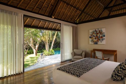 a bedroom with a bed and a large window at Akilea Villas Bali in Uluwatu