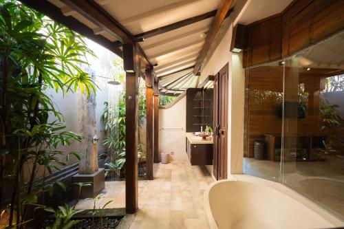 a bathroom with a tub and some plants at Akilea Villas Bali in Uluwatu