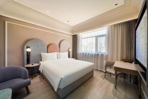 a hotel room with a bed and a flat screen tv at Mercure Qingdao Downtown in Qingdao
