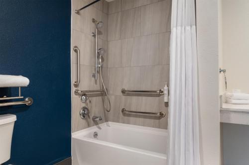a bathroom with a shower and a white bath tub at Spark by Hilton Watertown, NY in Watertown