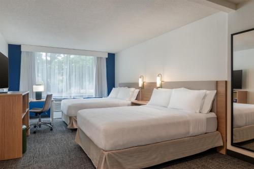 a hotel room with two beds and a desk at Spark by Hilton Watertown, NY in Watertown