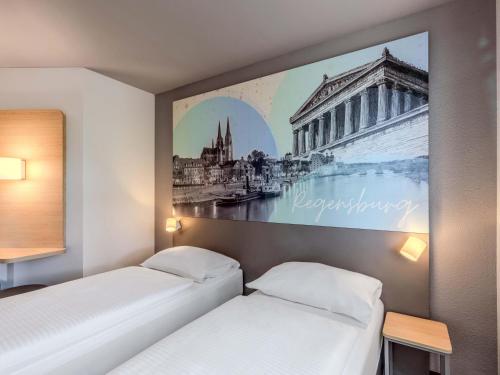 two beds in a room with a picture on the wall at B&B HOTEL Regensburg-Ost in Regensburg