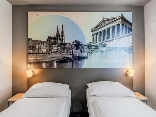 two beds in a room with a picture on the wall at B&B HOTEL Regensburg-Ost in Regensburg