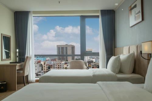 a hotel room with two beds and a large window at Hùng Vương Hotel - Stay 24h in Móng Cái