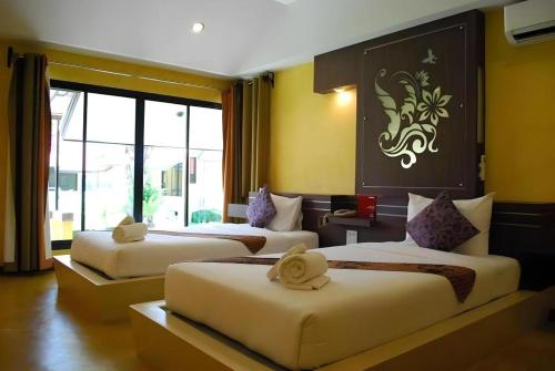 a hotel room with three beds and a window at Tanisa Resort in Na Dhung