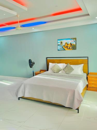 a bedroom with a large bed with colorful ceilings at Yoyo Kunda in Banjul