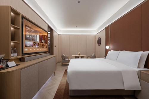 a hotel room with a bed and a flat screen tv at Orange Crystal Hotel Kunming Haile World in Kunming