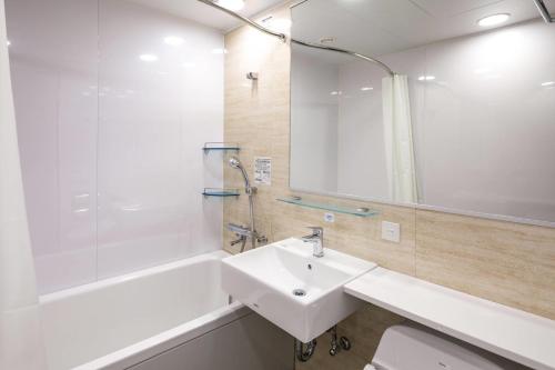 a bathroom with a sink and a tub and a mirror at Comfort Hotel Nagoya Shinkansenguchi in Nagoya