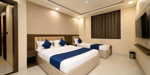 a bedroom with two beds with blue and white pillows at Hotel Rich Comfort Ajmer in Ajmer