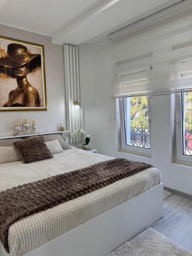 a white bedroom with a large bed and a window at Angel Luxury Apartment in Kikinda