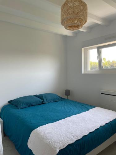 a bedroom with a blue and white bed and a window at Préchacq-les-Bains in Préchacq