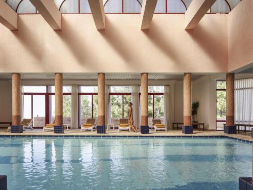 a woman walks by a swimming pool in a hotel at Grand Mercure Petra in Wadi Musa