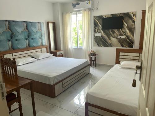a bedroom with two beds and a flat screen tv at Bright Nest Service Villa Munroe in Kollam