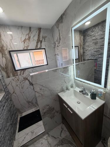 a marble bathroom with a sink and a mirror at Alvin Relax in El Cajon