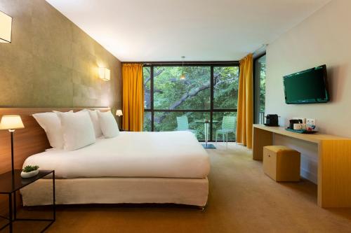 a hotel room with a bed and a large window at Moulin de Vernègues Hôtel & Spa in Mallemort