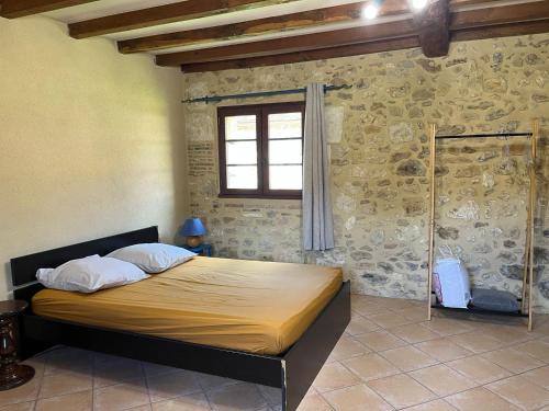 a bedroom with a large bed in a stone wall at Chez Fayolle in Montagnac-la-Crempse
