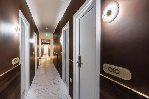a hallway with a door and a clock on the wall at La Maison Parliament by BQA in Budapest